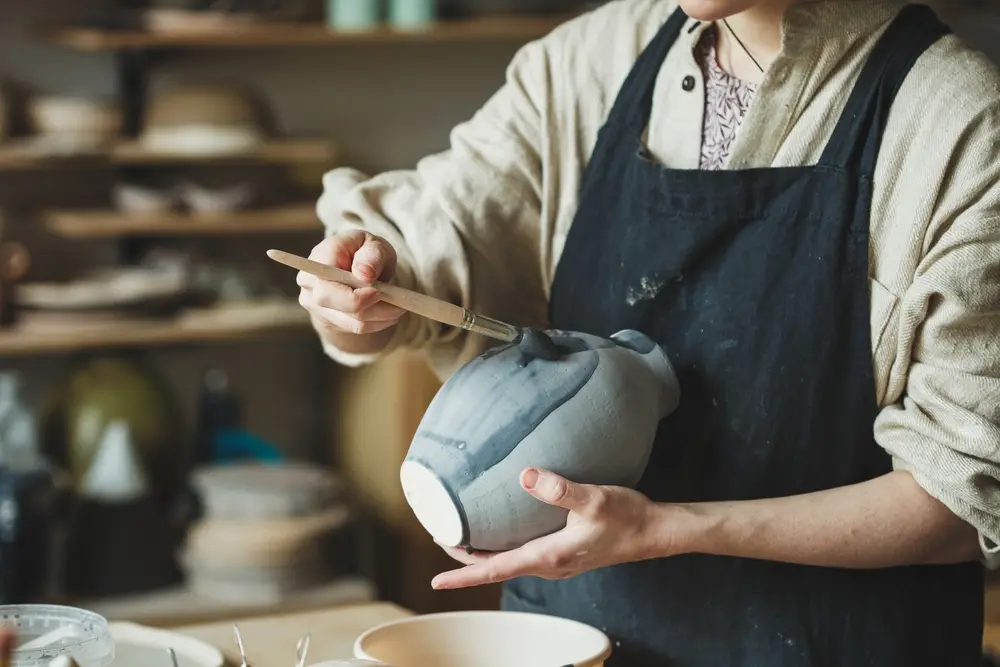 man painting ceramic pot